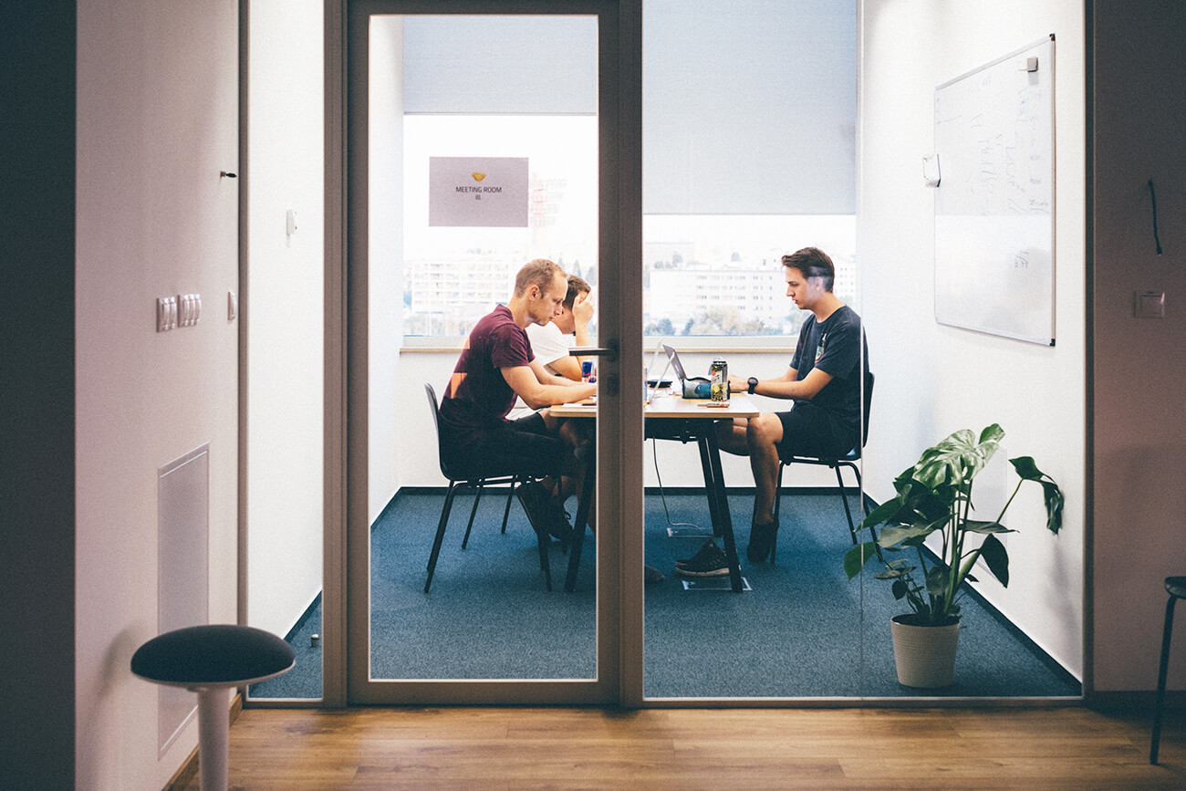 photo from a slido hackathon depicting three colleagues sitting around a table working on a new project together